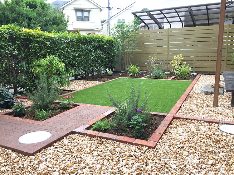 人工芝を中心に、レンガの植栽スペースを設けたお手入れをしやすいお庭
